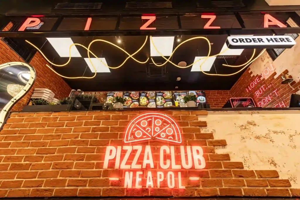 Sculptural amber round neon flex LED pendant above pizzeria counter